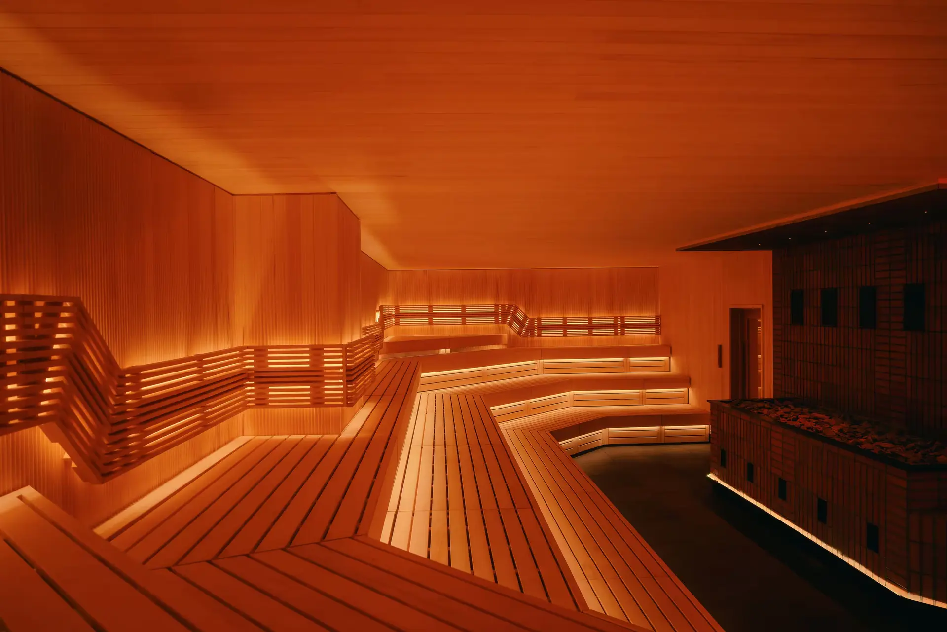 Tiered wooden benches and warm lighting in the sauna at Othership Williamsburg.