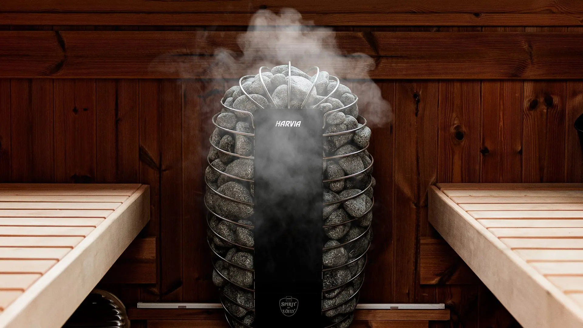 Steam rising from a Harvia heater set between two sauna benches