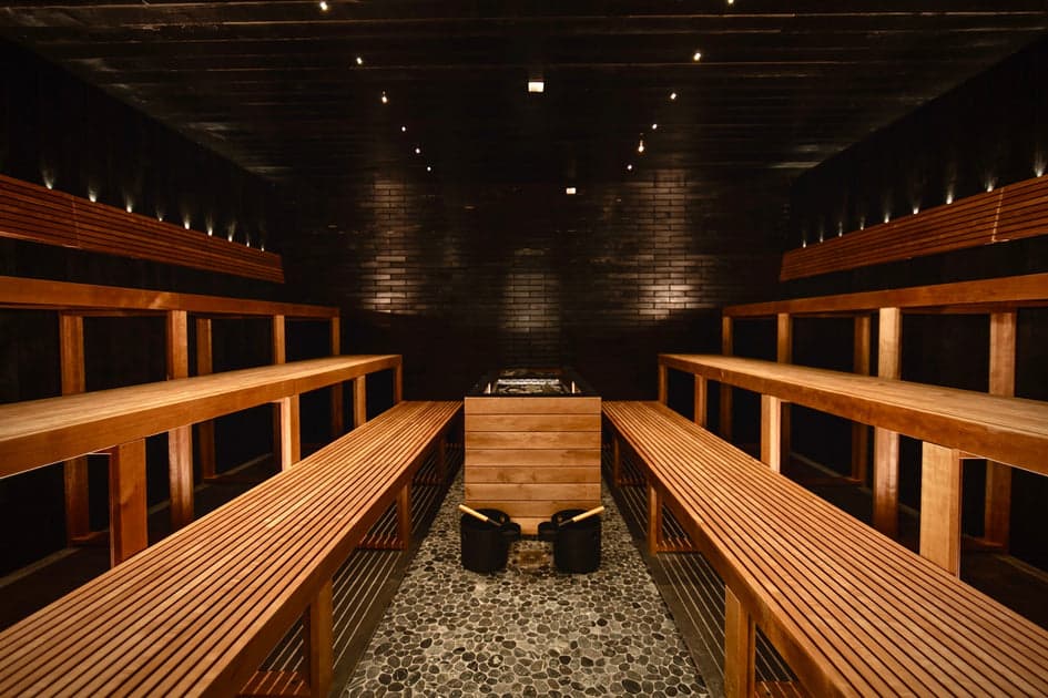 Public bathhouse sauna with dramatic dark ceiling and warm lighting