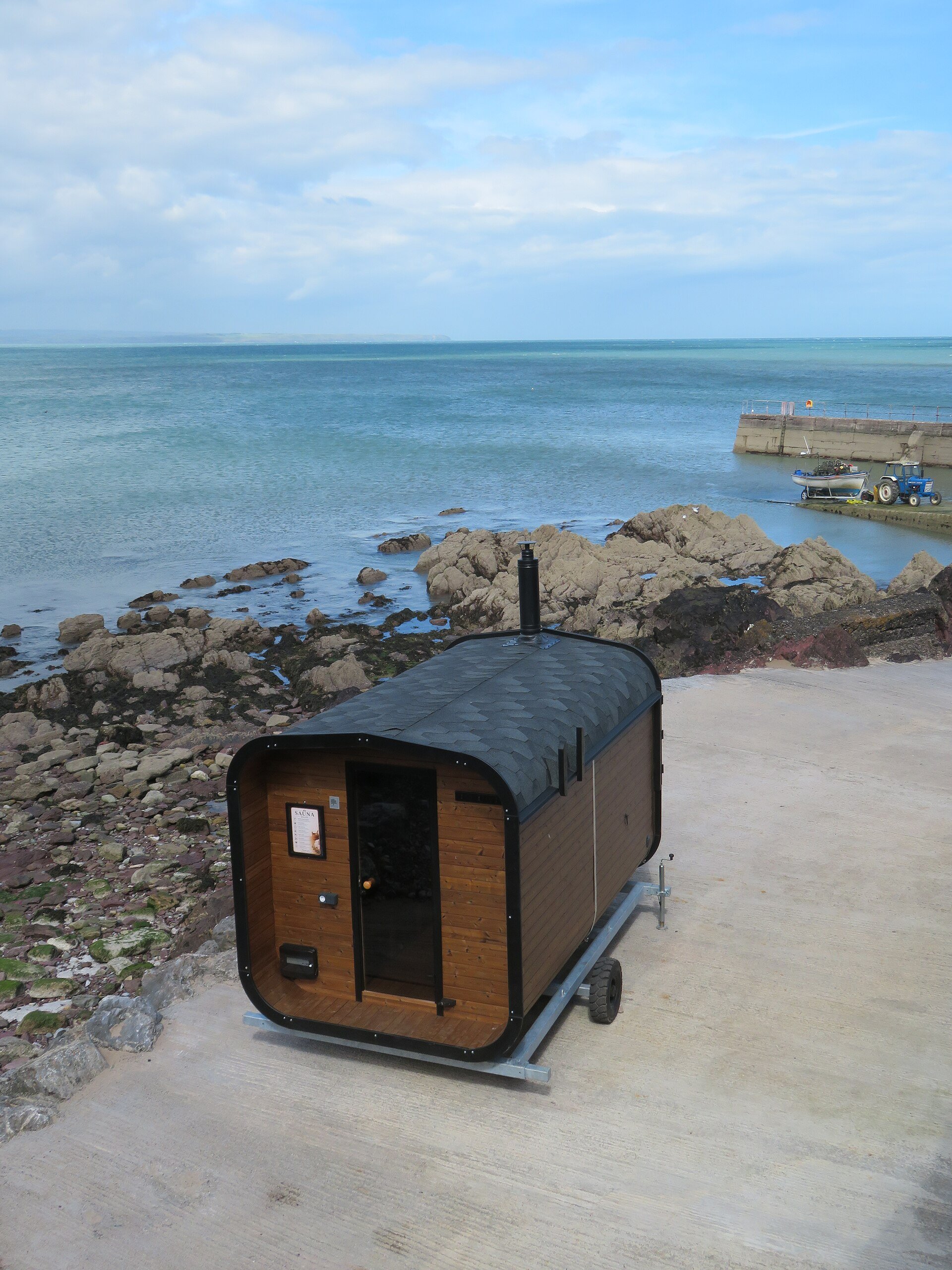 A portable wood-clad sauna on the harbor wall at Knockadoon, County Cork, Ireland, above the sea