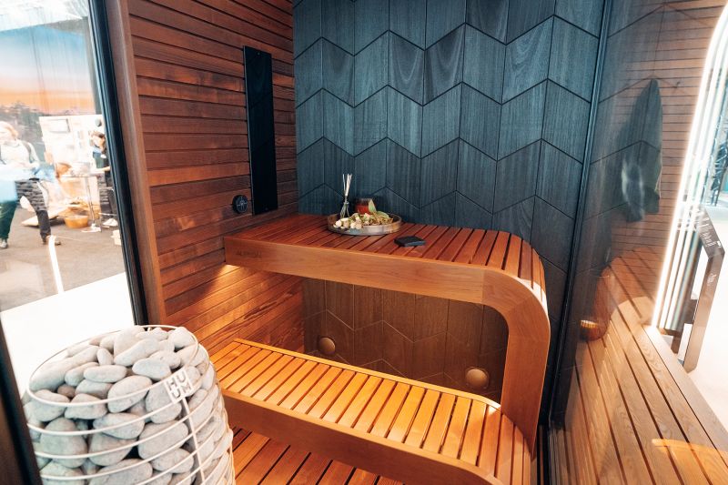Kumerad puidust lavad, infrapunapaneel ja kividega täidetud keris Auroomi Outdoor Spa näitusemudelis