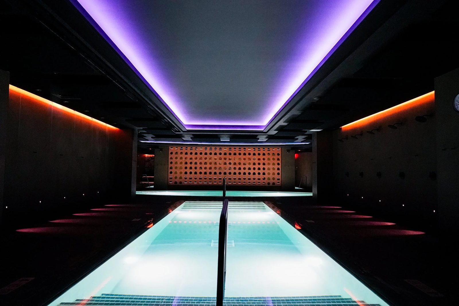 Long thermal pool at Bathhouse Atlantic Avenue, Brooklyn, lit by a purple LED ceiling cove and warm wall sconces, ahead of the May 16, 2026 opening