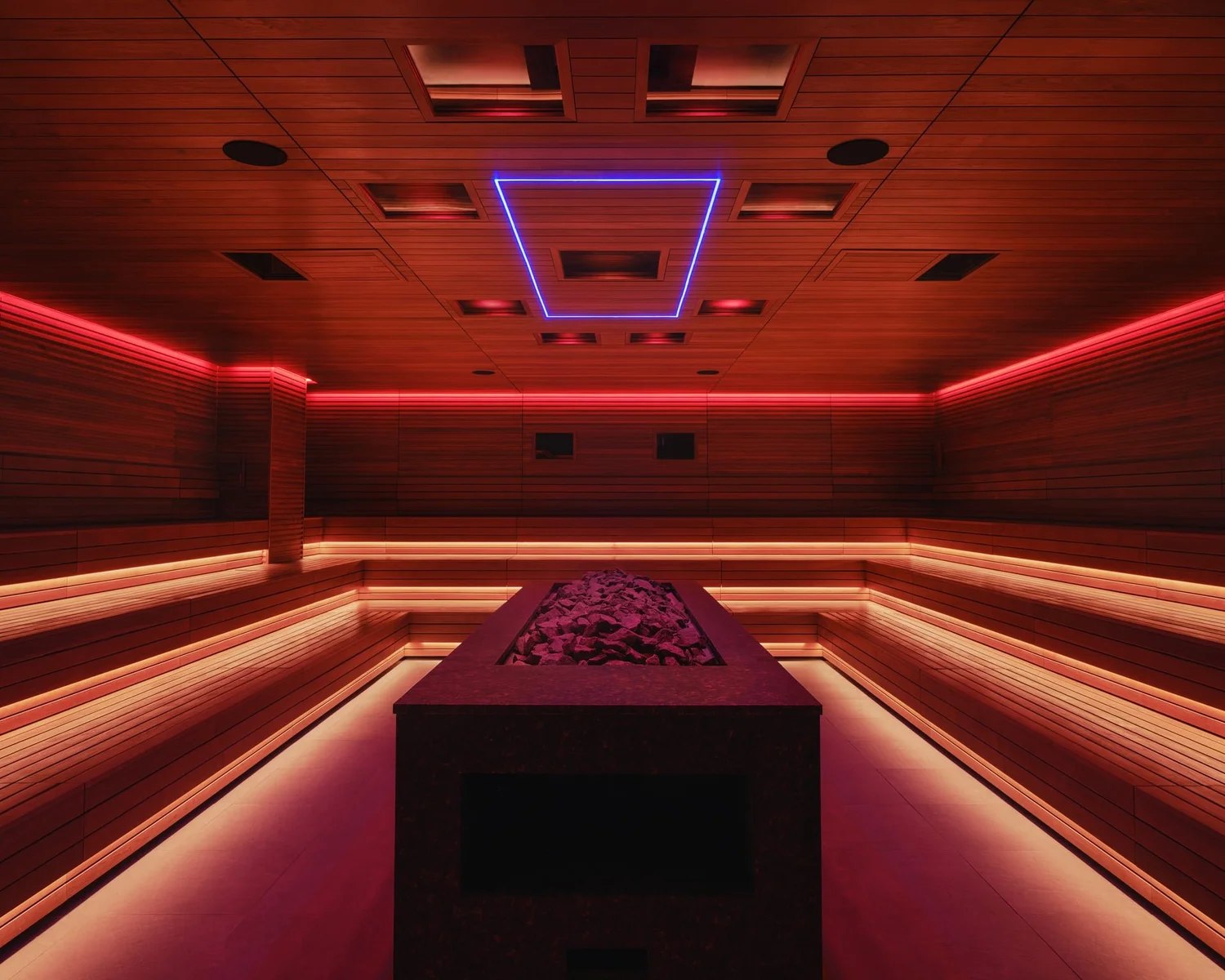 Tiered benches and a large stone heater inside Bathhouse Philadelphia’s event sauna