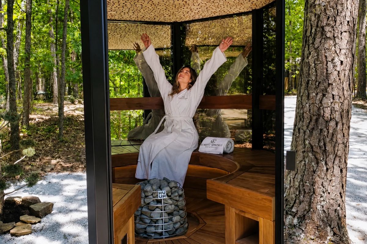 Guest enjoying the Haljas Single glass sauna interior at Forest Springs Resort with forest views through glass walls
