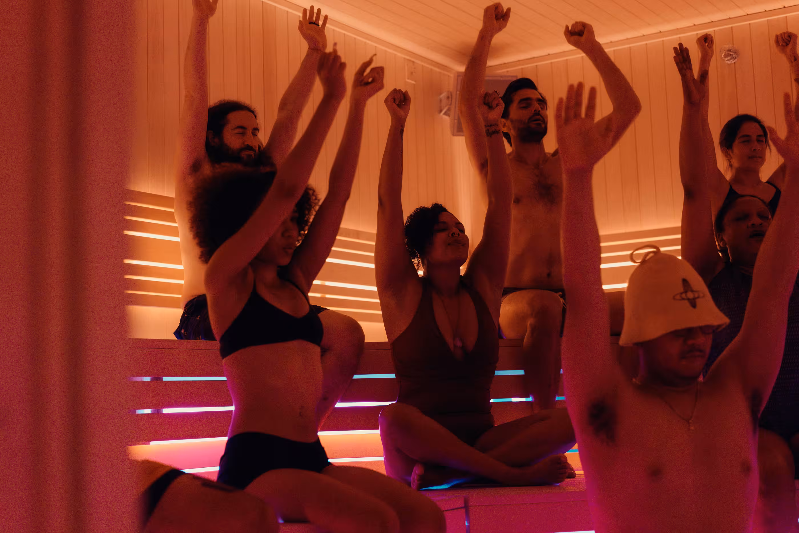 Guests raise their arms during a guided sauna class at Othership Flatiron.