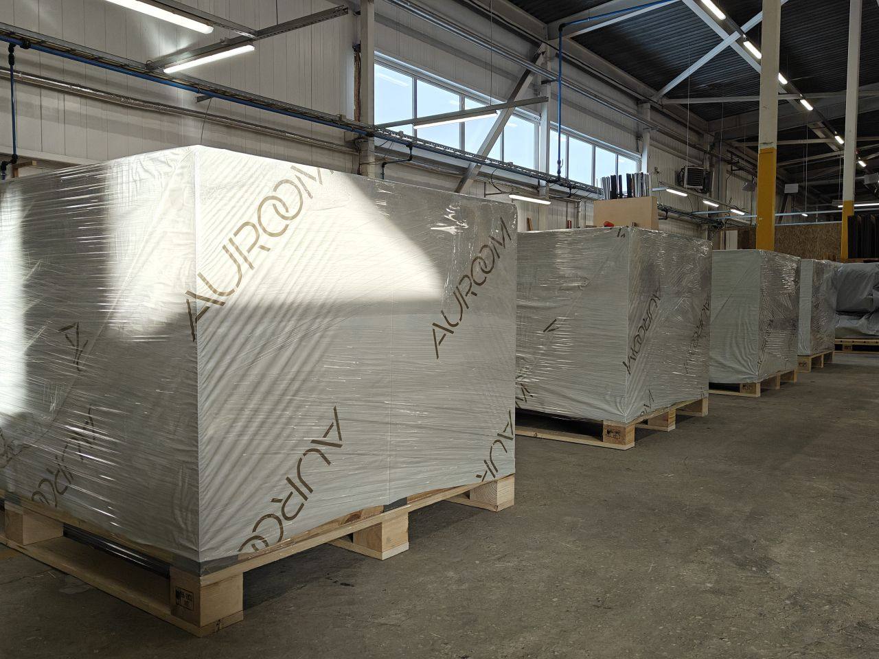 Auroom-branded sauna kits flat-packed and wrapped on shipping pallets in the factory, ready for transport to the build site