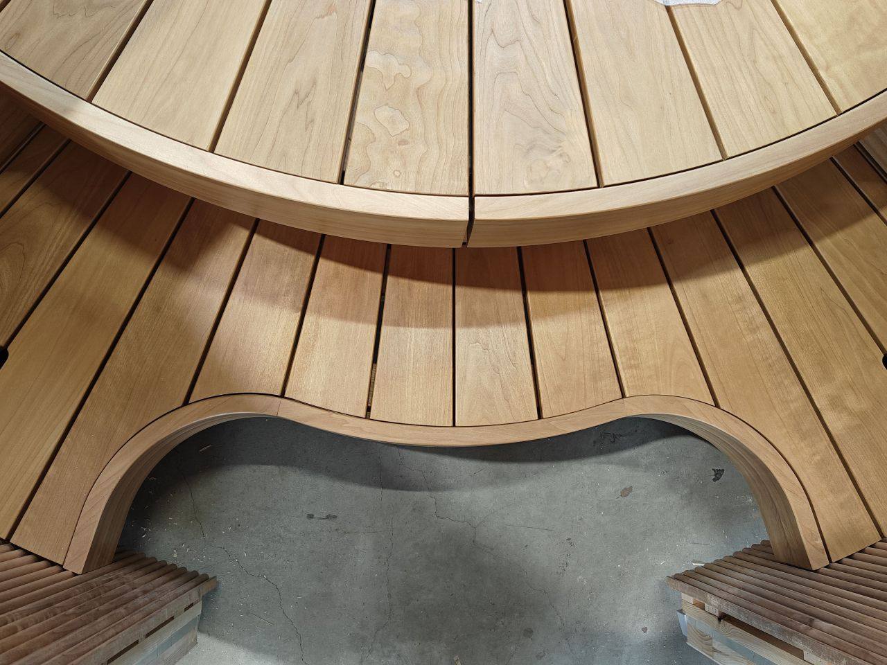 Detail of a precision-engineered circular Auroom sauna bench with curved wooden slats and integrated lighting channel